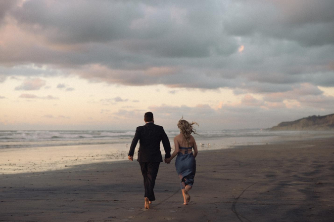 couple running on the sand captured by a beach elopement photographer
