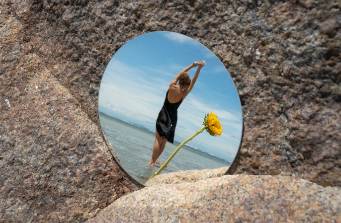 a photo is capture in mirror with a girl and flower