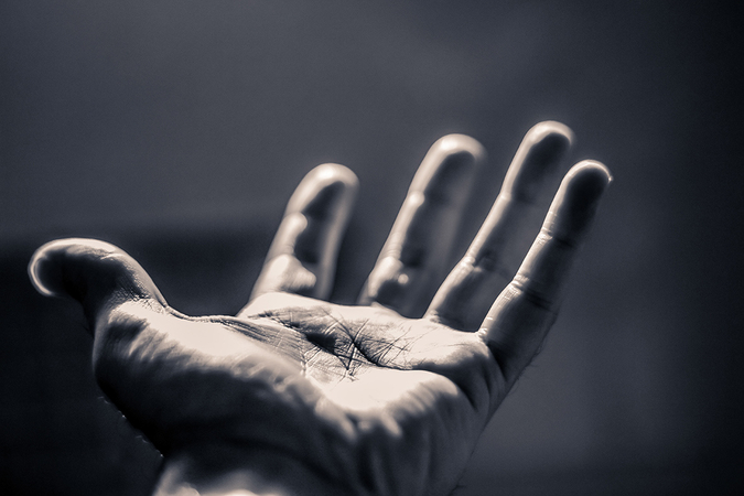 Outstretched hand in dramatic black and white lighting.