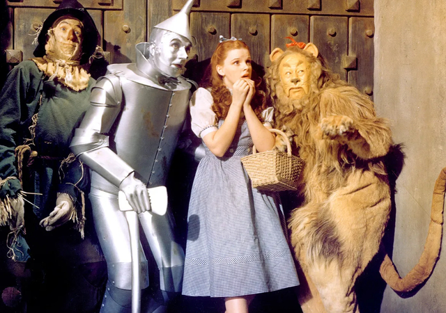 Four actors portraying characters from The Wizard of Oz in a studio setting