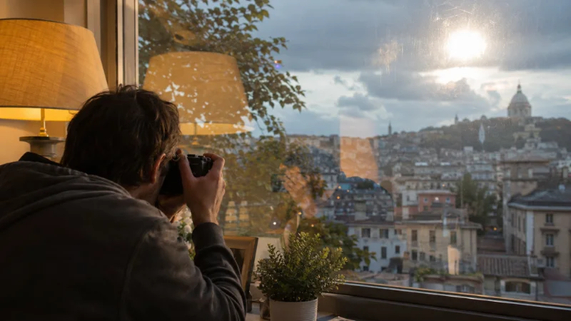 photographer taking a city photo through reflective window glass