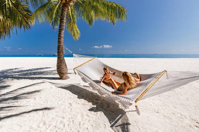 Family enjoying a sunny vacation day on a tropical beach with palm trees