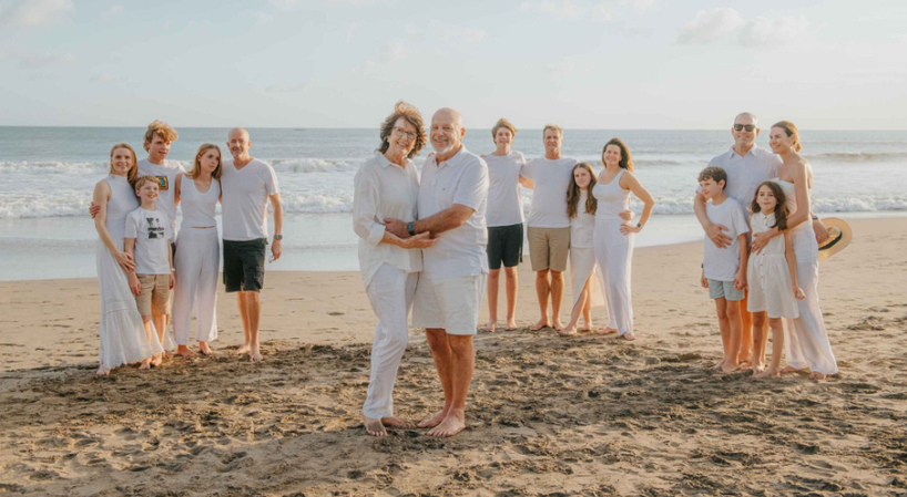 Coordinated family wearing matching white outfits on a sunny beach shore